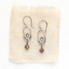 The brown zircon wanderer hoop earrings styled on tan linen