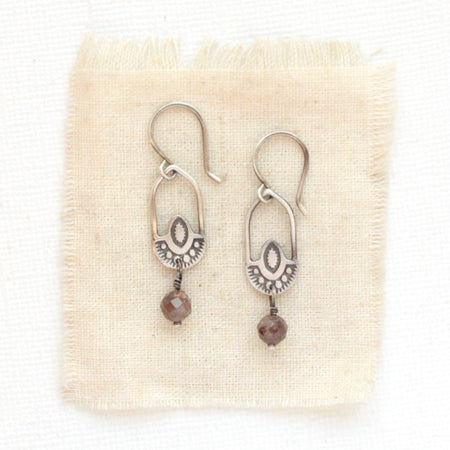 The brown zircon wanderer hoop earrings styled on tan linen