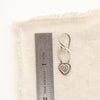 A layered heart earring next to a ruler for size reference