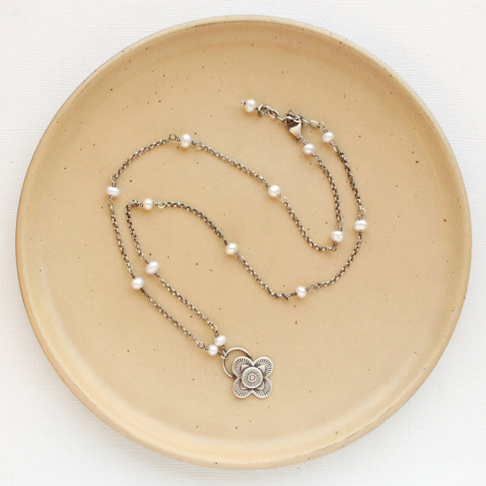 The layered talara pearl necklace styled on a tan plate to show the adjustable lobster clasp closure
