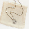 The layered talara pearl necklace styled on tan linen
