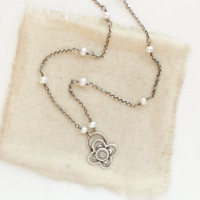 The layered talara pearl necklace styled on tan linen