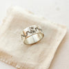 The stamped mountain range ring styled on tan linen