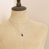 A mannequin wearing the garnet charm necklace