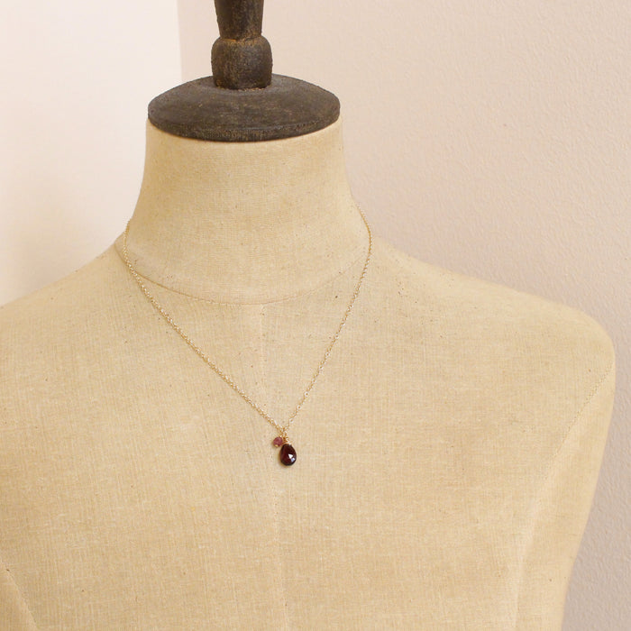 A mannequin wearing the garnet charm necklace