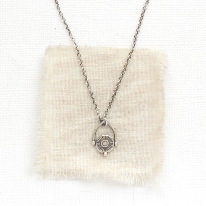 The mini talara shield necklace styled on tan linen