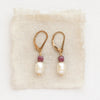 The pearl and ruby gold earrings styled on tan linen