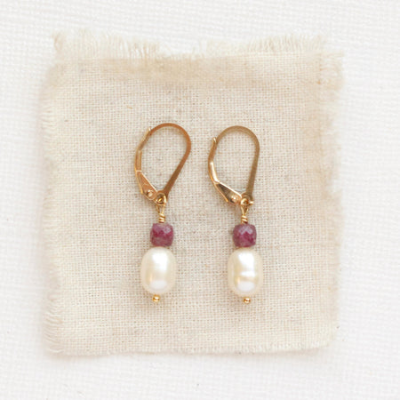 The pearl and ruby gold earrings styled on tan linen