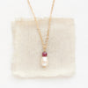 The pearl and ruby gold necklace styled on tan linen