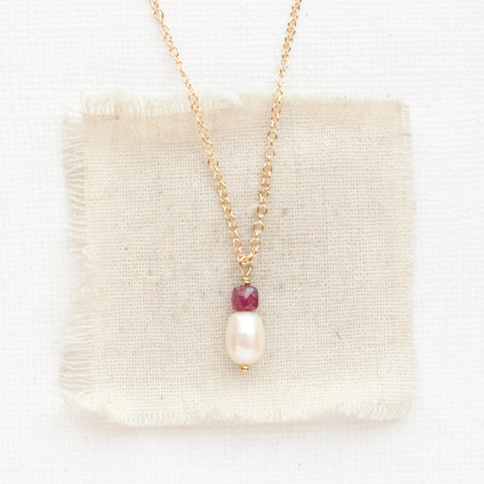 The pearl and ruby gold necklace styled on tan linen