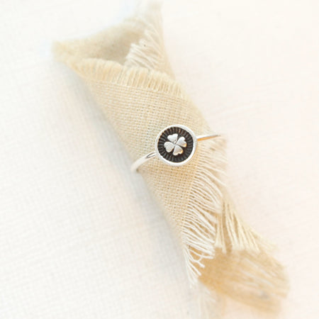 The clover stacking ring styled on rolled tan linen