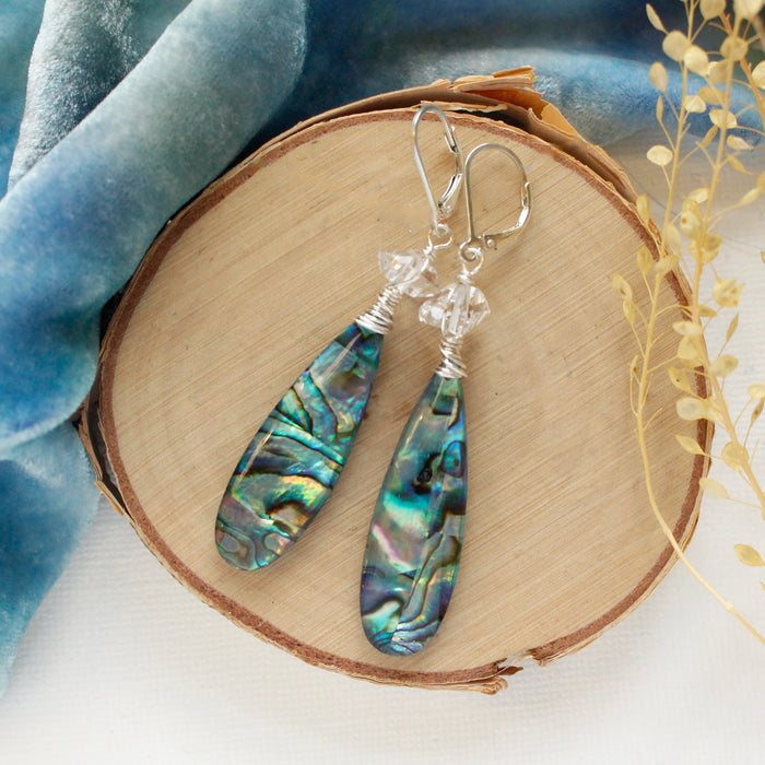 The abalone herkimer diamond statement earrings styled on wood with blue velvet and dried grass