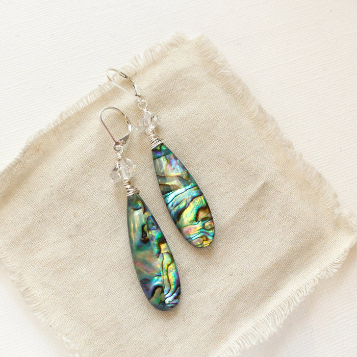 The abalone herkimer diamond earrings styled on tan linen
