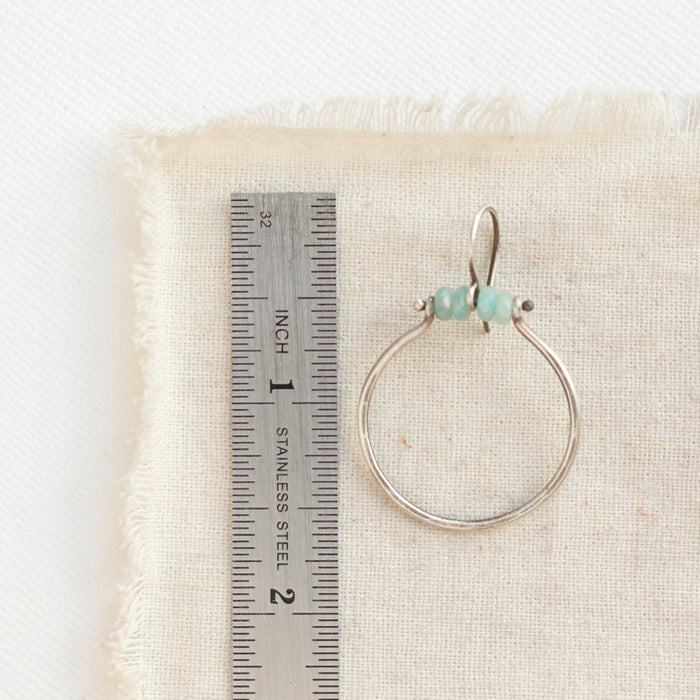 A amazonite halo hoop earring next to ruler for size reference