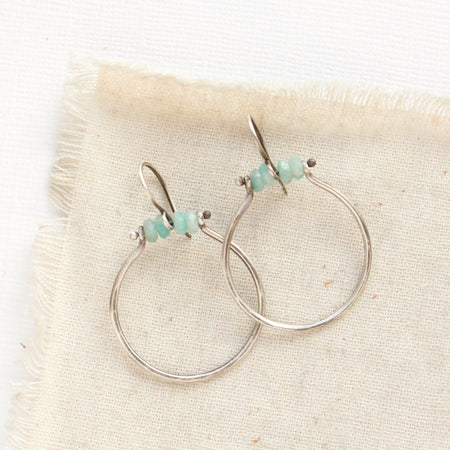 The amazonite halp hoop earrings styled on tan linen