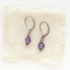 The perfect wrapped amethyst earrings styled on tan linen
