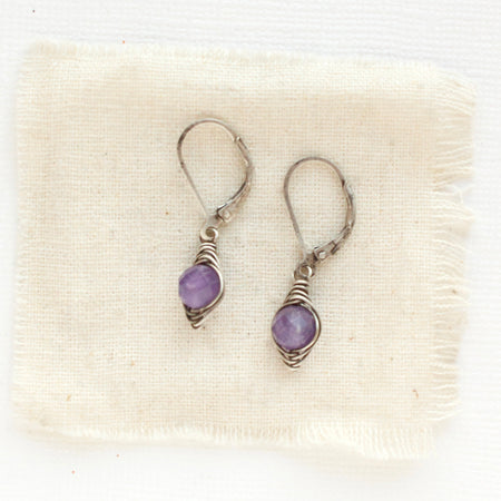 The perfect wrapped amethyst earrings styled on tan linen