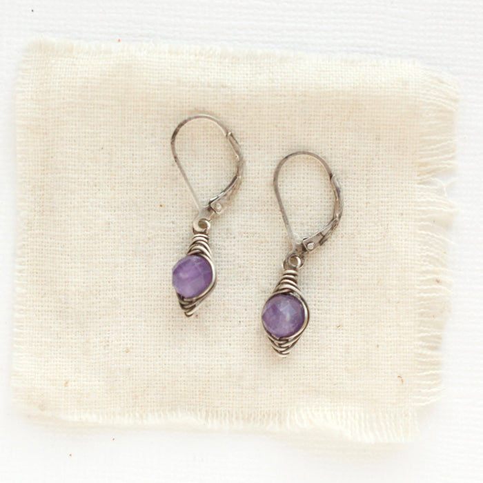 The perfect wrapped amethyst earrings styled on tan linen