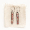 The andesine beaded bar earrings styled on tan linen