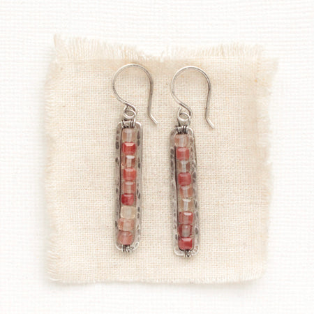 The andesine beaded bar earrings styled on tan linen