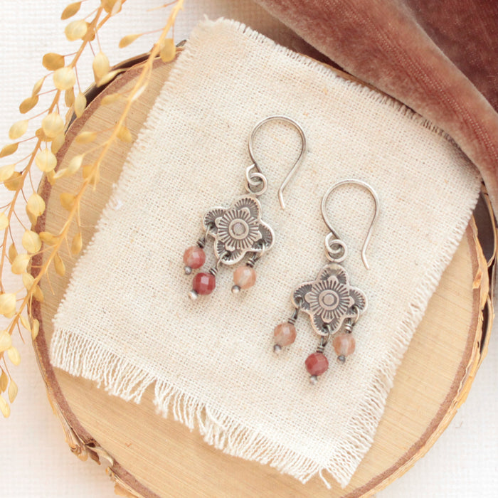 The mini talara andesine earrings styled on wood with orange velvet and dried grass