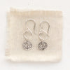 The aspen leaf hoop earrings styled on tan linen