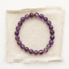 The beaded amethyst stretch bracelet styled on tan linen