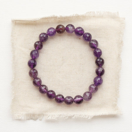 The beaded amethyst stretch bracelet styled on tan linen