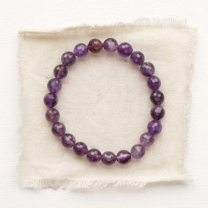 The beaded amethyst stretch bracelet styled on tan linen