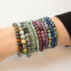 A bunch of beaded bracelets being worn on a wrist