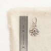 A big musana earring next to a ruler for size reference
