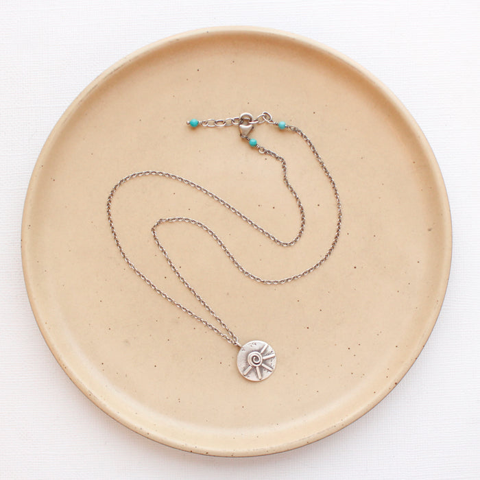 The big musana necklace styled on a tan plate to show the adjustable lobster clasp closure
