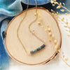 The black ethiopian opal bar necklace styled on wood with blue velvet and dried grass