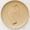 The black ethiopian opal bar necklace styled on a tan plate to show the adjustable lobster clasp closure