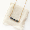 The black ethiopian opal bar necklace styled on tan linen