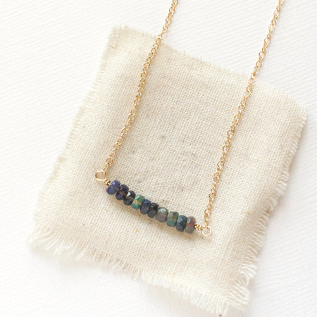 The black ethiopian opal bar necklace styled on tan linen