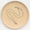 The black tourmaline jolie necklace styled on a tan plate to show the adjustable lobster clasp closure