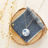 The blue bloom vintage plate necklace styled on wood with blue linen and dried grass