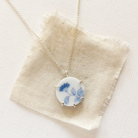 The blue bloom vintage plate necklace styled on tan linen