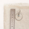 A zircon silver hoop earring next to a ruler for size reference