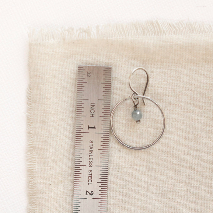 A zircon silver hoop earring next to a ruler for size reference