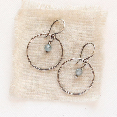 The zircon silver hoop earrings styled on tan linen