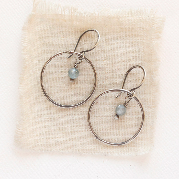 The zircon silver hoop earrings styled on tan linen