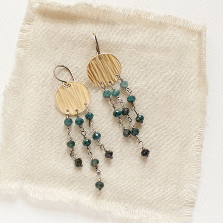The grandidierite mythos chandelier earrings styled on tan linen