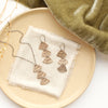 The bronze asmi trio triangle earrings styled on a tan plate with the matching necklace