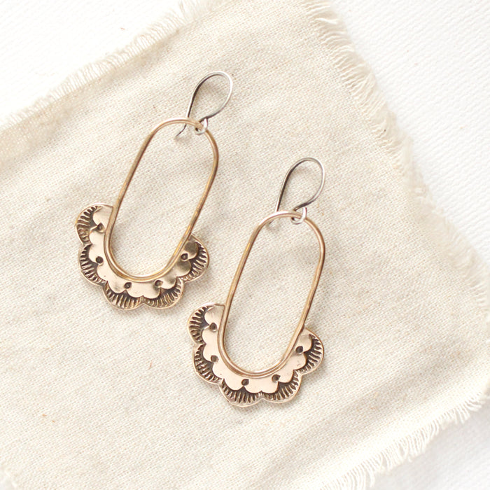The bronze columbine hoop earrings styled on tan linen 