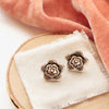 The bronze layered cactus flower post earrings styled on wood with linen and orange velvet