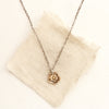 The bronze mini cactus flower necklace styled on tan linen