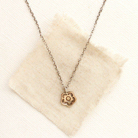 The bronze mini cactus flower necklace styled on tan linen