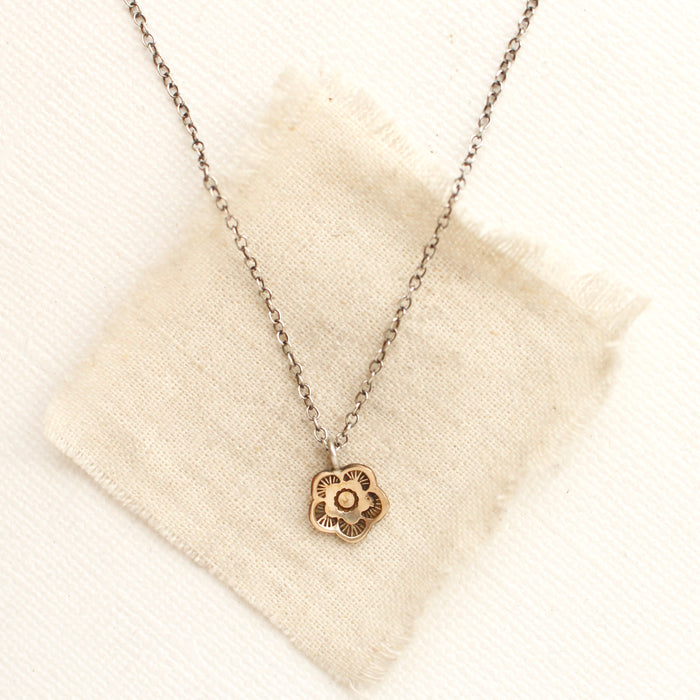 The bronze mini cactus flower necklace styled on tan linen